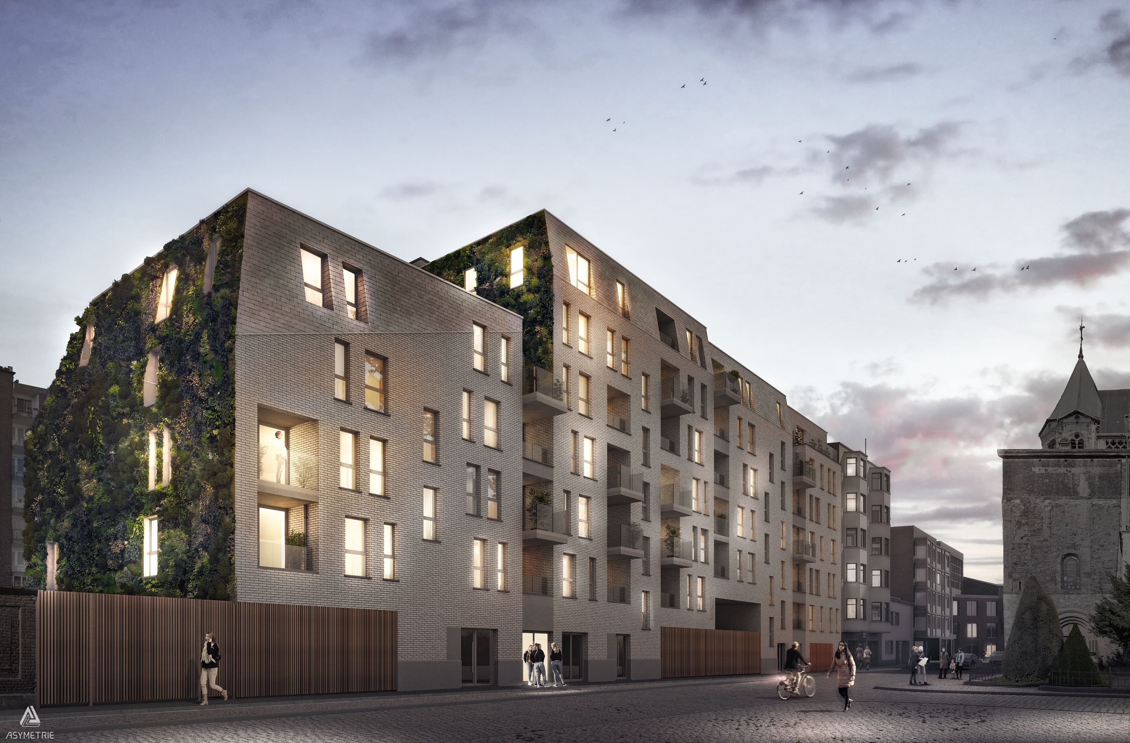 Immeuble résidentiel contemporain en briques, avec balcons et façade végétalisée, vu au crépuscule. Le projet s’intègre dans un environnement urbain animé, à proximité d’un bâtiment historique et d’une rue pavée.